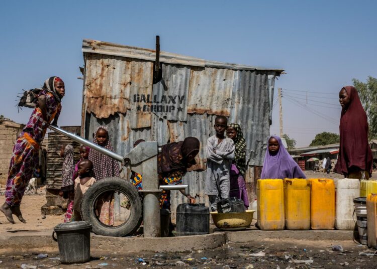 Tyttö pumppaa vettä Unicefin poraamasta kaivosta Maidugurin pakolaisleirillä Nigeriassa.