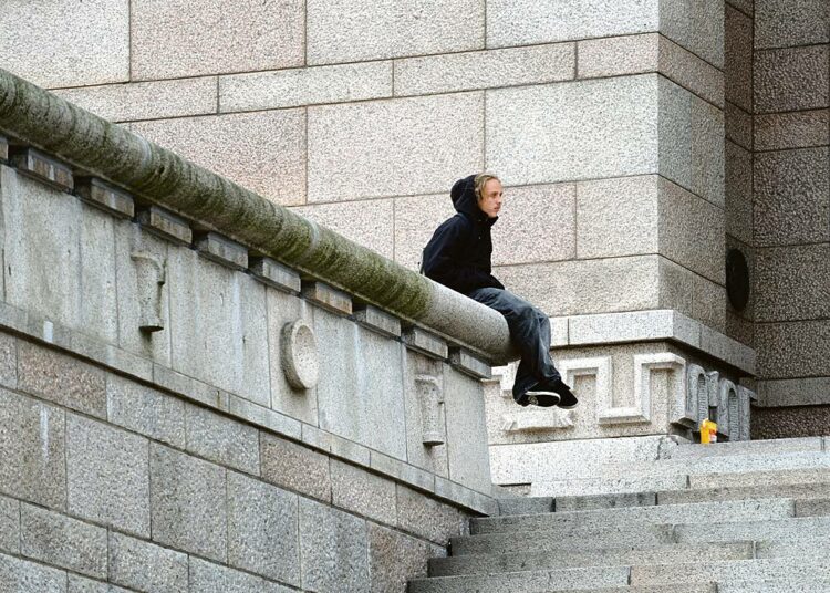 Hallitus ei osaa vastata suurimpaan turvallisuusuhkaan, syrjäytymiseen. Kuvassa nuori mies istuu Eduskuntatalon portailla Helsingissä.
