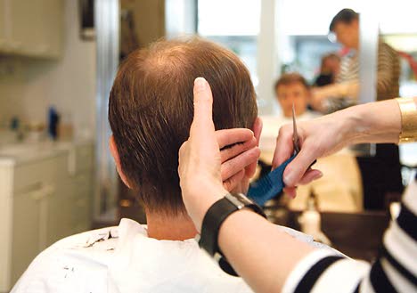 Taantumaa ei saa käyttää tekosyynä ja siirtää työhyvinvointia lisääviä ratkaisuja. Kuvassa parturi ja asiakas Helsingissä.