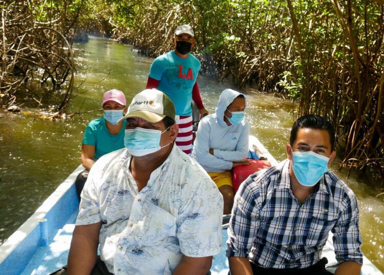 Häädön uhkaamien perheiden jäseniä matkaa veneellä pitkin mangrove-kanaalia San Luis La Herraduran kunnassa El Salvadorin rannikolla. Cuatra Vientosin asukkaat asettuivat 20 vuotta sitten maalle, jota uskoivat valtion maaksi. Nyt yksi maan suurimmista pankeista väittää omistavansa tontin.