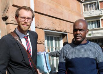 Journalisti Jeffrey Moyo (oikealla) asianajajansa Doug Coltartin kanssa Bulawayon käräjäoikeuden edustalla. Moyoa syytetään maahanmuuttolain rikkomisesta, mutta hän tulkitsee syytteen pelkäksi häirinnäksi.