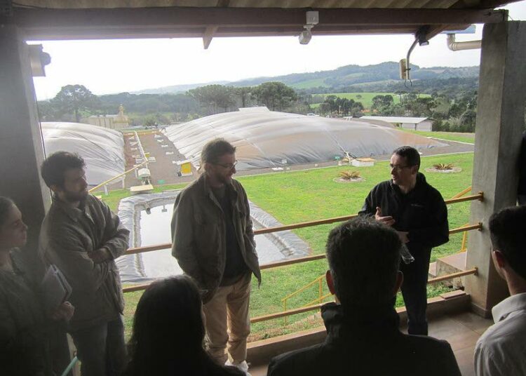 Airton Kunz, Embrapan sika- ja siipikarjajaoksen tutkimusjohtaja selittää sikalajätteen käsittelyjärjestelmää, taustalla häämöttää 10 000 sian São Roquen sikatila.