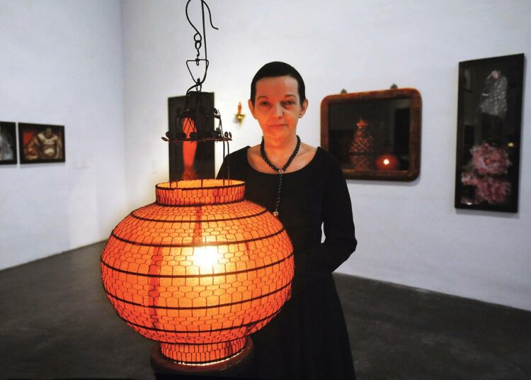 Marita Liulia on nauttinut maailman kaikkien pääuskontojen valosta. Tässä hän poseeraa näyttelyn itämaisessa nurkkauksessa kungfutselaisuutta käsittelevien töidensä edessä.