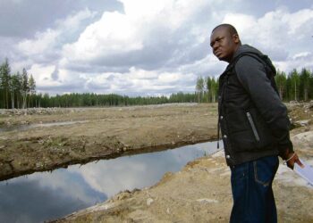 Nigerialainen ympäristöaktivisti Philip Jakpor katseli Ylä-Lumijärven maisemia järven ohitusojan penkalta Talvivaaran kaivoksen vieressä Sotkamossa. Taustalla siintävä aukea hiekkakenttä syntyi, kun kaivosyhtiö kaapi turvekerroksen pois metallimönjän saastuttamalta suolta.