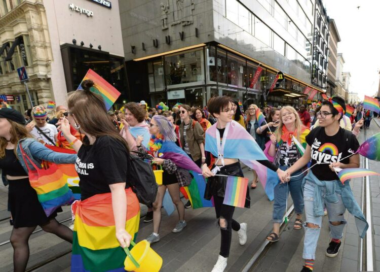 Helsinki Pride -kulkue Aleksanterinkadulla. Mukana sateenkaaren värien lisäksi myös vaaleansini-vaaleanpuna-valkoinen trans-lippu.