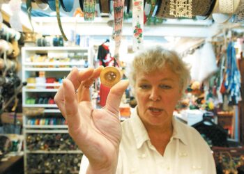 Ritva Lehtinen Punainen Lanka -liikkeestä esitteli tammesta tehtyä nappia Hakaniemen hallin täyttäessä 90 vuotta.