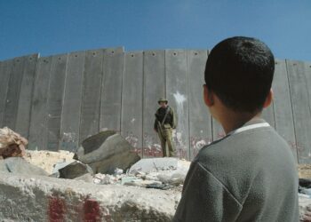 Palestiinalaispoika katseli israelilaista sotilasta, joka vartioi Israelin hallituksen Länsirannalle rakentamaa kahdeksan metriä korkeaa suojamuuria.