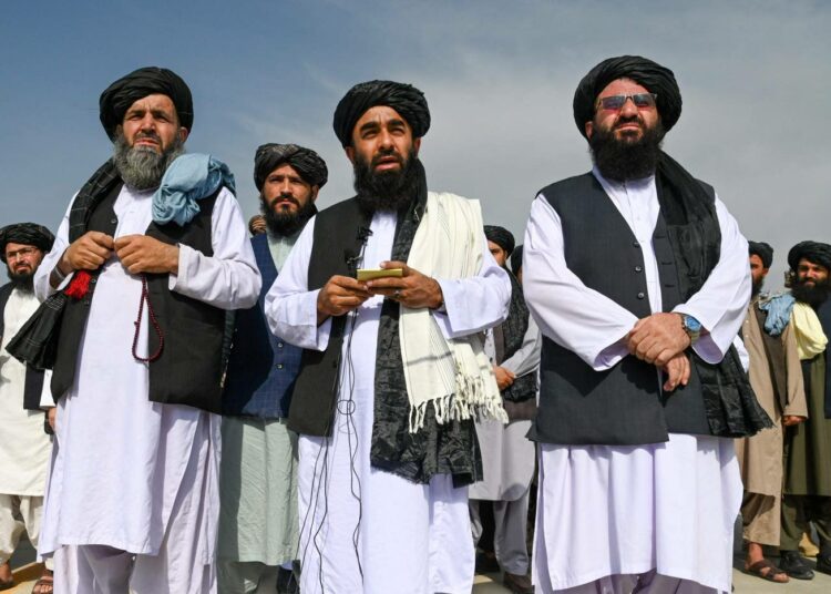Talebanin edustaja Zabihullah Mujahid (keskellä) puhui Kabulin lentokentällä.