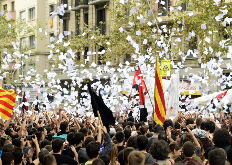 Mielenosoittajat heittivät äänestyslappuja ilmaan protestoidessaan Espanjaa johtavan kansanpuolueen Katalonian-haaran toimiston edessä tiistaina.