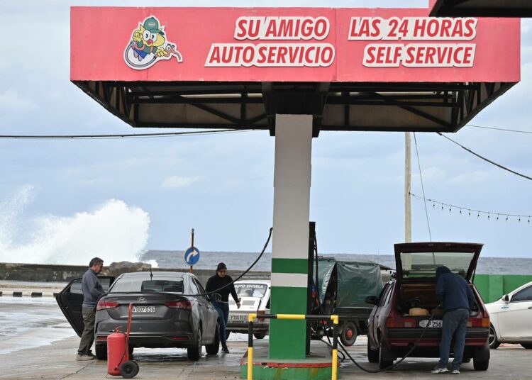 Autoilijat tankkaavat dollareita hyväksyvällä huoltoasemalla Havannassa.