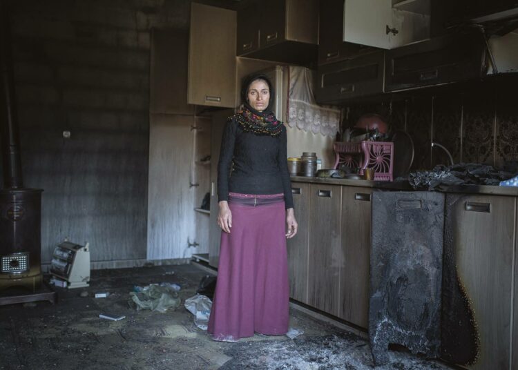 Leila tuhotun talonsa keittiössä. Hän vakuuttaa pysyvänsä kodissaan ja rakentavansa sen uudestaan.