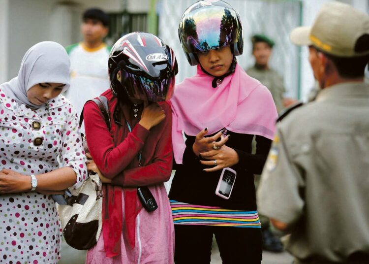 Kaikki muslimit eivät halua välttämättä kasvattaa lapsiansa uskonnolliseen koodistoon. Islamilainen sharia-poliisi nuhtelee nuoria tyttöjä länsimaisesta pukeutumisesta katutarkastuksessa Indonesian Banda Acehissa joulukuussa 2009.