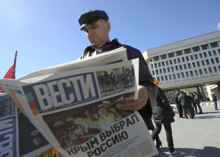 Mihail Osmolovskij luki lehdestä reportaasia venäläismielisten voitonjuhlista Krimin alueparlamentin edustalla Simferopolissa maanantaina.