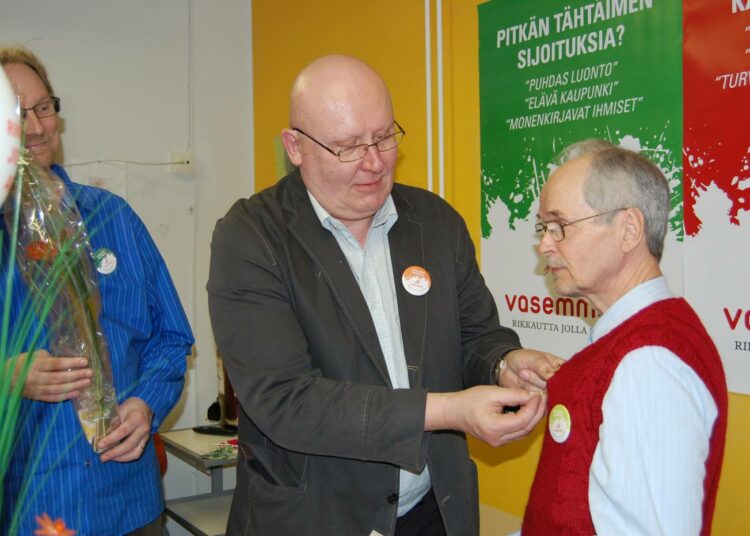 Ennen piirihallituksen kokousta pidetyssä avoimien ovien tilaisuudessa piirin puheenjohtaja Jarmo Ritanen (vas.)  ja toiminnanjohtaja Jukka Kinos luovuttivat puolueen kultaisen ansiomerkin vaajakoskelaiselle puolueaktiiville Väinö Tervolle.