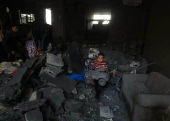 Palestiinalaisperhe etsi tavaroitaan Israelin ilmaiskussa tuhoutuneesta rakennuksesta Gazassa maanantaina.