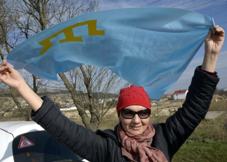 Nainen heilutti tataarien lippua Simferopolin kaupungin laidalla Stroganofgan tataarikylässä ennen Krimin kansanäänestystä maaliskuun puolivälissä.