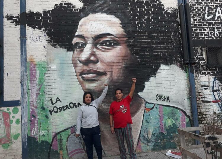 Lucy Mercado ja Marcos Basualdo taustanaan seinämaalaus, joka esittää maaliskuussa Rio de Janeirossa murhattua brasilialaista poliitikkoa ja ihmisoikeusaktivistia Marielle Francoa.