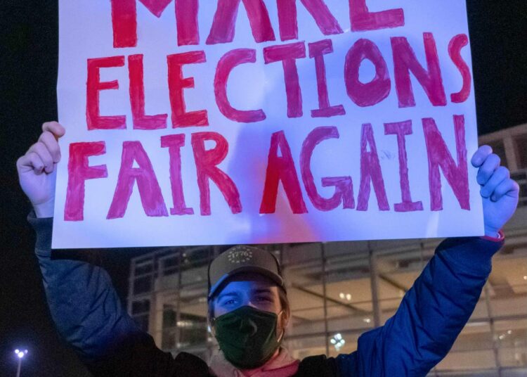 Vielä ääntenlaskun jatkuessa Detroitissa Trumpin kannattaja kantaa kylttiä, joka vaatii reiluja vaaleja