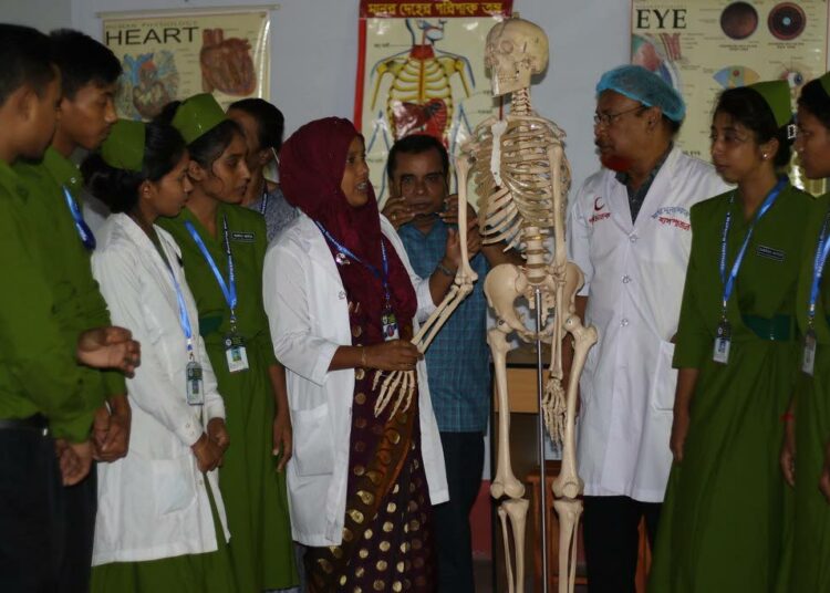 Anatomian oppitunti Moimunan sairaanhoitoinstituutissa. Ensimmäinen opiskelijaryhmä koostuu kahdestakymmenestä vähäosaisesta maalaisnuoresta. Useimmat ovat tyttöjä.