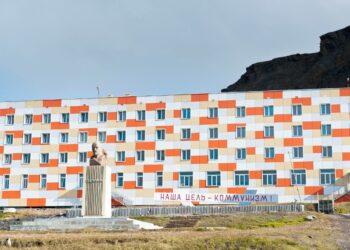 Neuvostoaikainen asuinrakennus Barentsburgissa Norjan Huippuvuorilla. Plakaatissa lukee: Tavoitteemme on kommunismi!