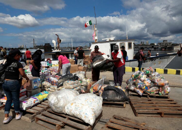 Granma 2.0 -aluksen aktivistit purkavat yhdessä satamatyöntekijöiden kanssa lahjoituksia Haiphongin laiturilla Havannan satamassa.