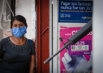 El Salvadorin Juayúan kylässä asuva nainen odottaa pääsyä apteekkiin, jonka ovella vartioi aseistettu sotilas. Armeija on tullut poliisin avuksi valvomaan karanteenisääntöjen noudattamista.