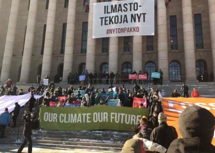 Greenpeacen kiipeilijät ripustivat eduskuntatalon pylväisiin banderollin. Kuvakaappaus Greenpeacen videosta.