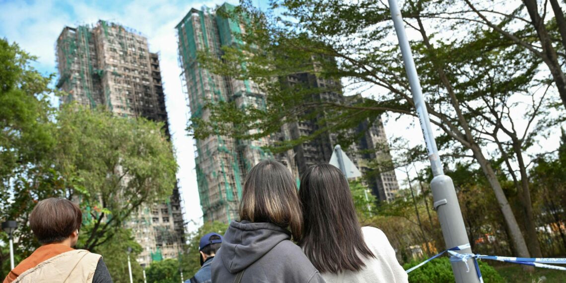 Hongkongilaiset nuoret katselivat tulipalossa mustuneita tornitaloja Tai Pon lähiössä joulukuun alussa.