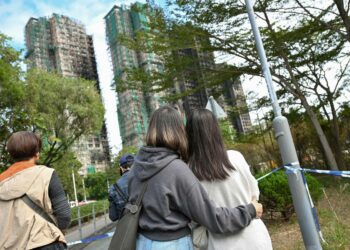 Hongkongilaiset nuoret katselivat tulipalossa mustuneita tornitaloja Tai Pon lähiössä joulukuun alussa.