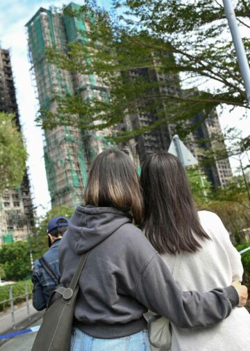 Hongkongilaiset nuoret katselivat tulipalossa mustuneita tornitaloja Tai Pon lähiössä joulukuun alussa.