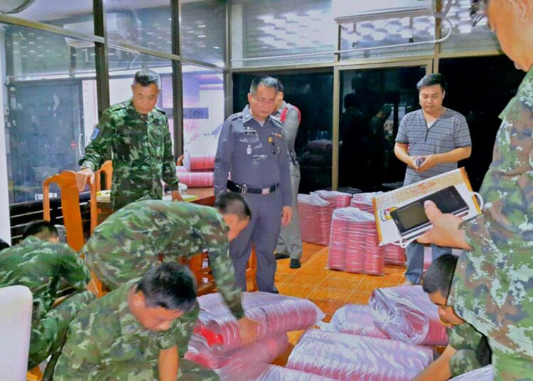 Thaimaalaiset sotilaat ja poliisit takavarikoimassa punaisia muovikulhoja maanantaina Nanin maakunnassa maan pohjoisosassa.