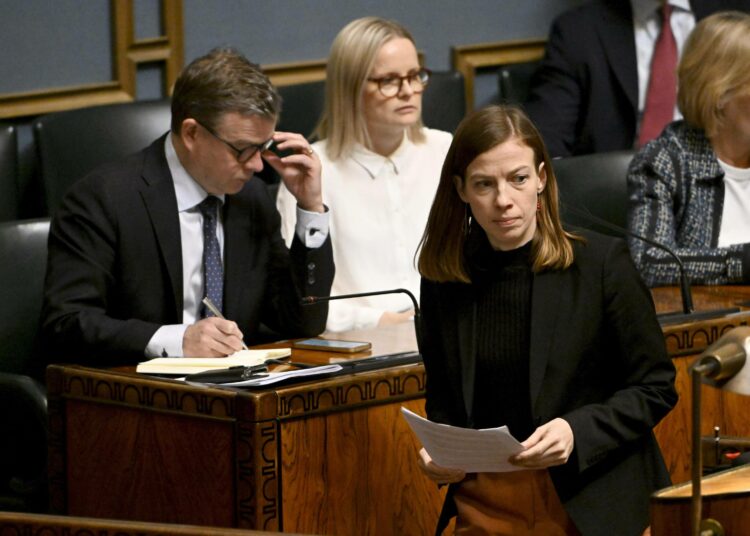 Li Andersson kuvattiin välikysymyskeskustelussa 20. helmikuuta. Taustalla pääministeri Petteri Orpo ja valtiovarainministeri Riikka Purra (ps.).