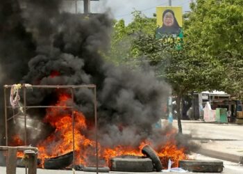 Dar es Salaamissa presidentti Samia Hassanin muotokuva roikkuu tolpassa, kadulla käryvät Samiaa vastaan protestoivien mielenosoittajien sytyttämät autonrenkaat.