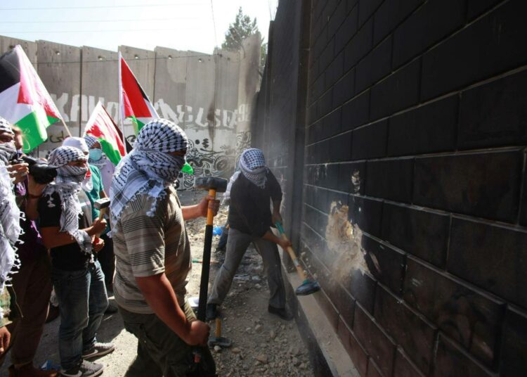 Palestiinalaisnuoret kävivät moukarein Israelin rakentaman ”turva-aidan” kimppuun Abu Disissä Jerusalemin rajalla. Heidän mielestään se on apartheid-muuri.