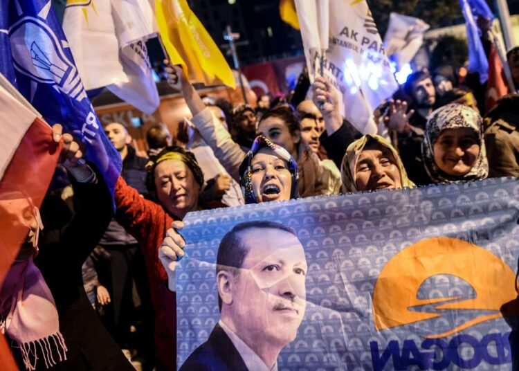 AKP-puolueen kannattajat juhlivat sunnuntai-iltana Istanbulissa presidentti Recep Tayyip Erdoganin kuvia kantaen.