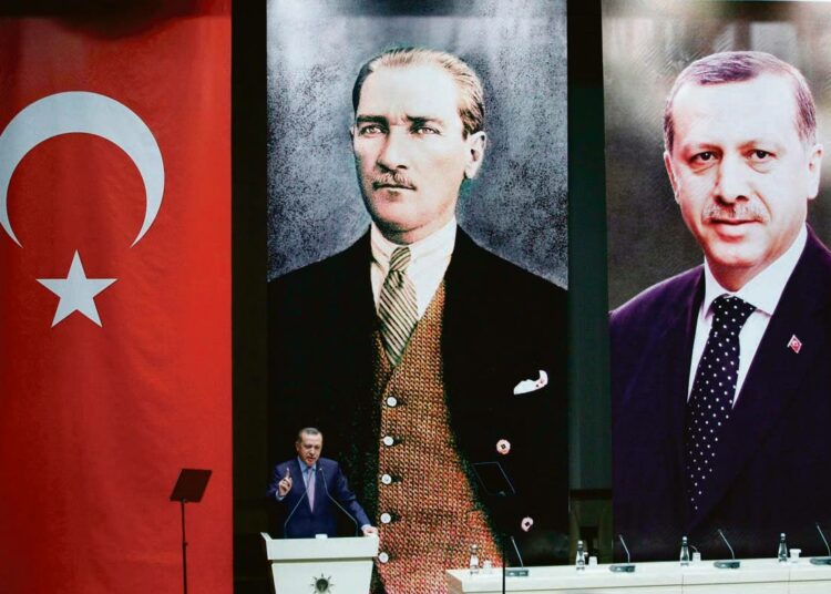 Turkin pääministeri Recep Tayyip Erdogan pitämässä puhetta takanaan Turkin lippu, Mustafa Kemal Atatürkin kuva ja hänen oma kuvansa.