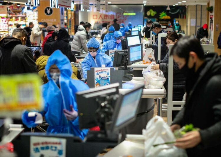 Myyjät ja asiakkaat ovat varautuneet suojavarusteilla supermarketissa Shenyangissa Kiinassa.