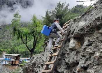 Nepalin Manangin alueella terveydenhoitaja kuljettaa rokotteita pitkin tulvissa romahtaneita teitä.
