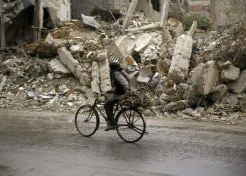 Mies pyöräilee ohi taistelujen vaurioittaman rakennuksen Doumassa lähellä Damaskosta.