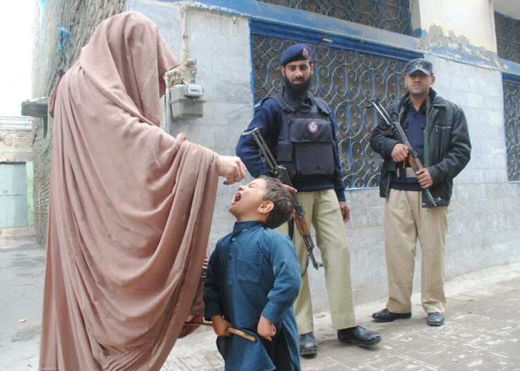 Pakistanin Peshawarissa nuori poika saa poliorokotteen suun kautta. Sotilaat valvovat, sillä ääri-islamistit vastustavat rokotuksia.