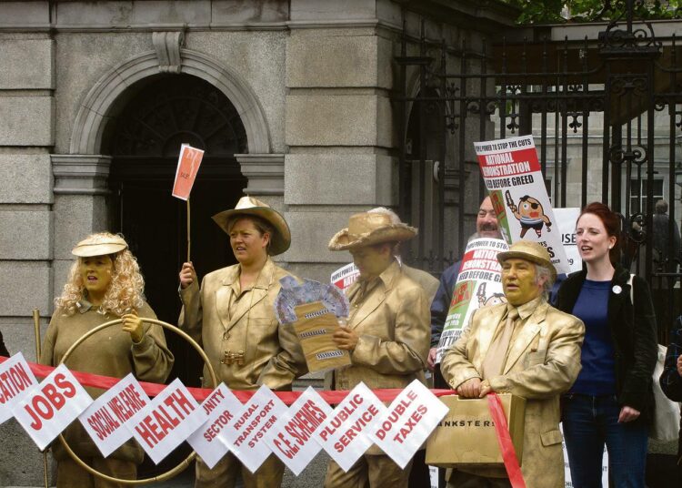 Keskiviikon mielenosoituksessa Irlannin parlamentin edessä  ?pankkiirit? iloitsevat Nama-suunnitelmasta, joka siirtäisi pankkien tappioita tuottavat paperit valtiolle.