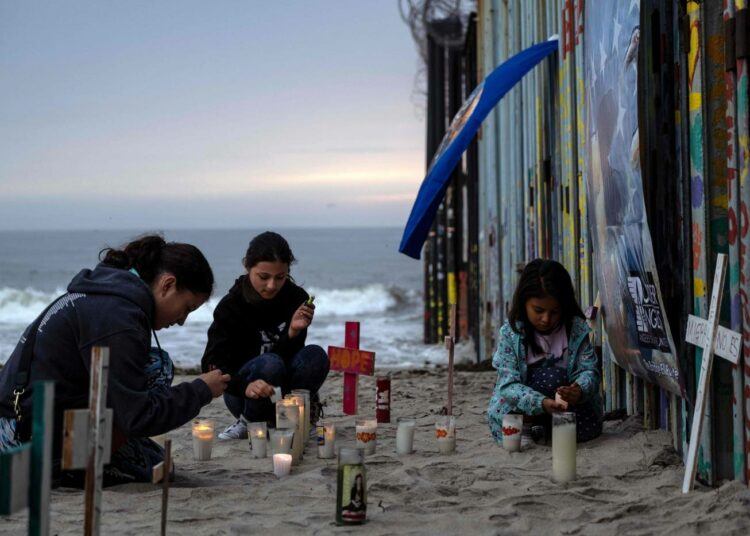 Tytöt sytyttivät lauantaina kynttilöitä Meksikon Playas de Tijuanassa niiden muistoksi, jotka kuolivat pyrkiessään Yhdysvaltoihin.
