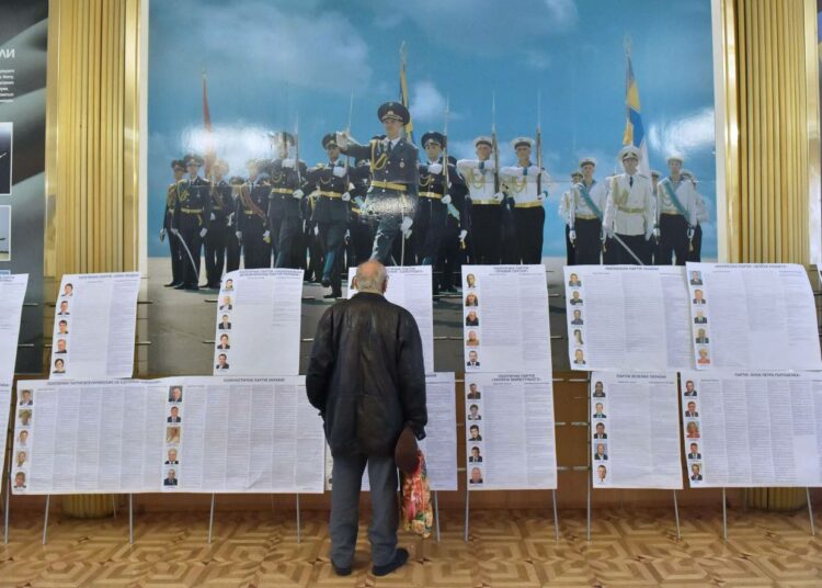 Mies tutki ehdokaslistoja vaalipaikalla Kiovassa sunnuntaina,