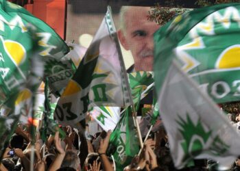 Sosialistien Pasok-puolueen kannattajat riemuitsivat, kun vaalivoittaja George Papandreou (jonka kasvot näkyvät ruudussa taustalla) saapui sunnuntai-iltana puolueen päämajaan.