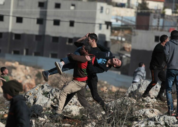 Palestiinalaiset kantavat Israelin sotilaiden luodeista haavoittunutta nuorta tammikuussa Jalazunin pakolaisleirissä Ramallahin lähellä.