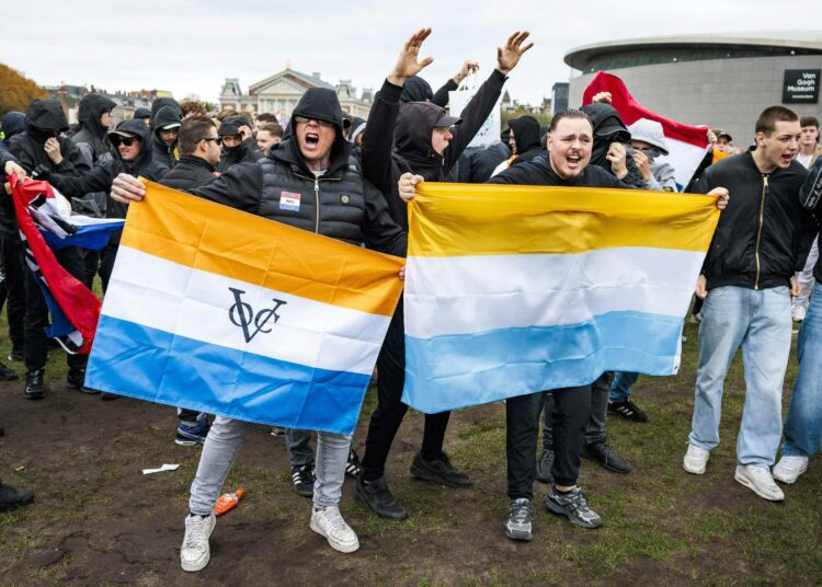 Maahanmuuttajien vastainen mielenosoitus Amsterdamissa lokakuussa. Vasemmanpuoleinen lippu on siirtomaavallan aikainen, 1600-luvulta peräisin oleva Hollannin Itä-Intian kauppakomppanian lippu.