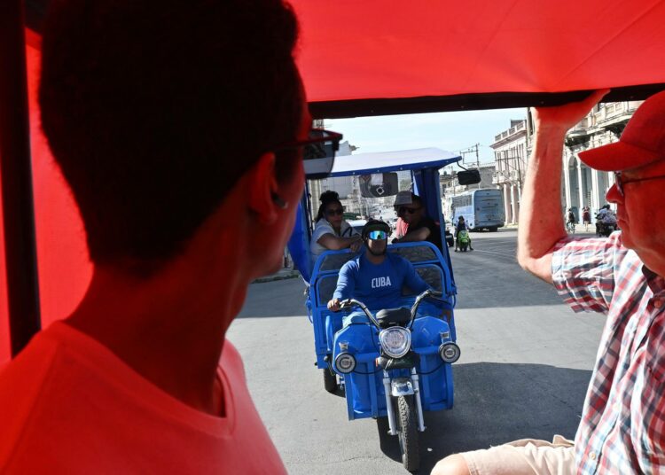 Turisti sähköisen kolmipyöräisen kyydissä Havannassa.