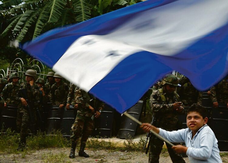 Hondurasilainen lapsi heiluttI lippua armeijan joukkojen edessä maan pääkaupungissa Tegucigalpassa heinäkuun puolessavälissä.
