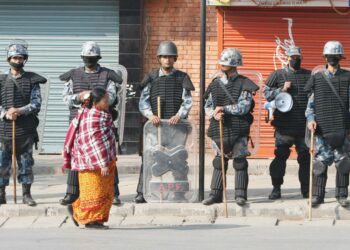 Nainen kävelee poliisiketjun ohi Kathmandussa maolaisten julistaman yleislakon aikana kolme viikkoa sitten.