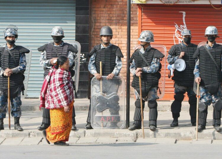 Nainen kävelee poliisiketjun ohi Kathmandussa maolaisten julistaman yleislakon aikana kolme viikkoa sitten.